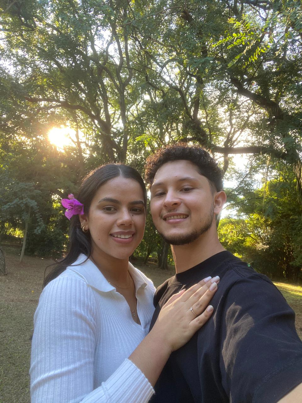 Andressa e Matheus sorrindo para a câmera em um parque ao pôr do sol